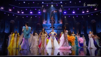 Varias mujeres vestidas con trajes de gala posan en un escenario iluminado con luces moradas