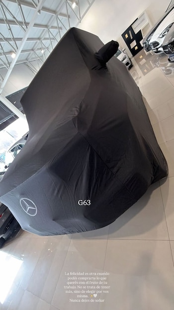 Una camioneta de lujo cubierta con una funda negra en un concesionario de autos. El logo de Mercedes-Benz es visible en la funda, junto con el texto 'G63'