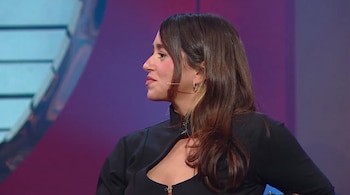 Perfil de Leticia Siciliani con ropa negra y micrófono de diadema sobre un fondo de estudio morado.
