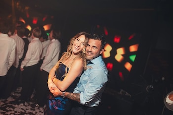 Micaela Viciconte, con cabello rubio ondulado y vestido azul, y Fabián Cubero, con camisa celeste, abrazados y sonriendo