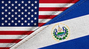 Las banderas de Estados Unidos y El Salvador están unidas por una costura sobre una textura de tela.