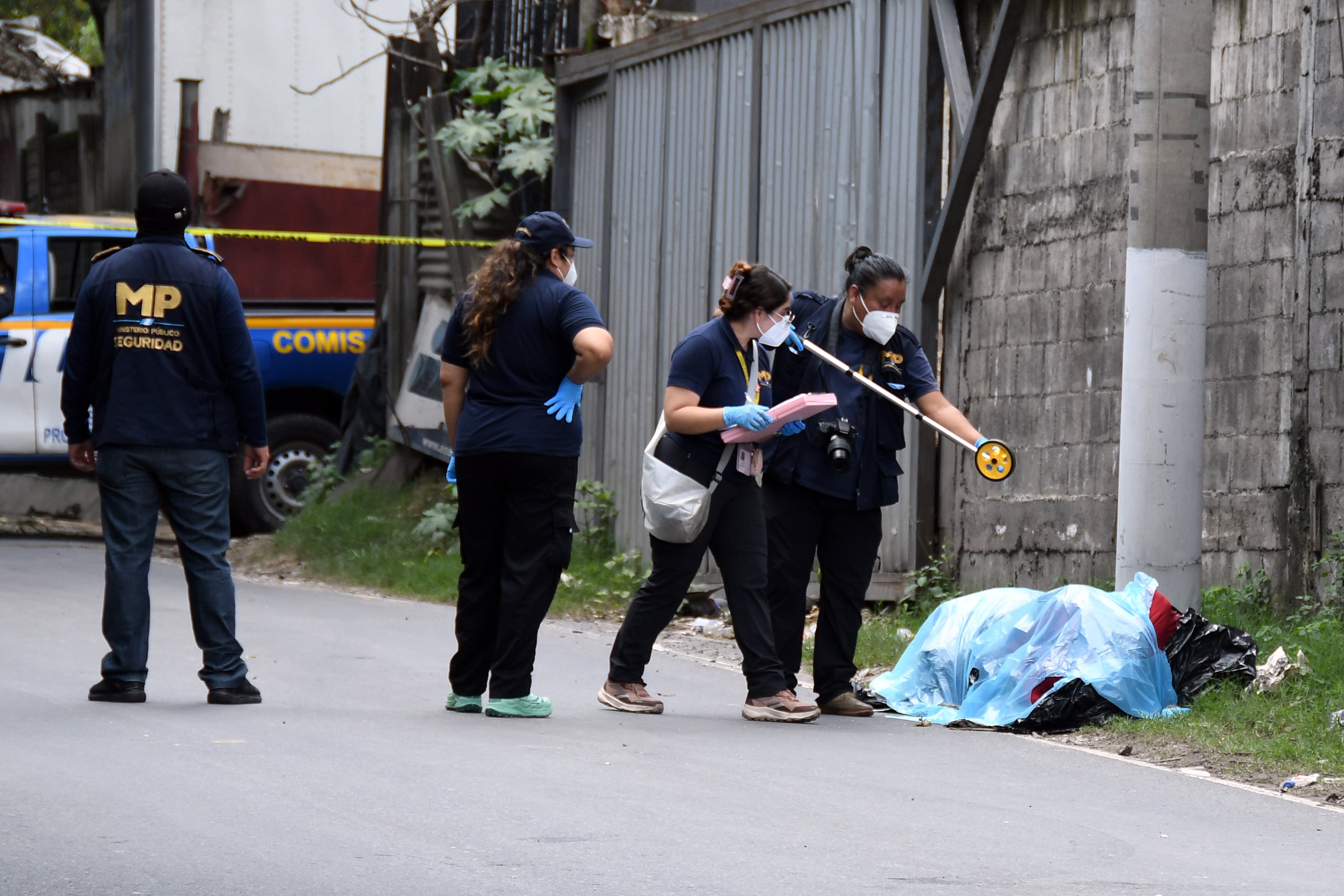 Fotografía que muestra a integrantes del Ministerio Público y de la Policía Nacional Civil inspeccionando dos cadáveres encontrados en bolsas plásticas y amarrados con lazos a un costado de la carretera antigua que conduce a Chinautla (Guatemala). EFE/ Alex Cruz
