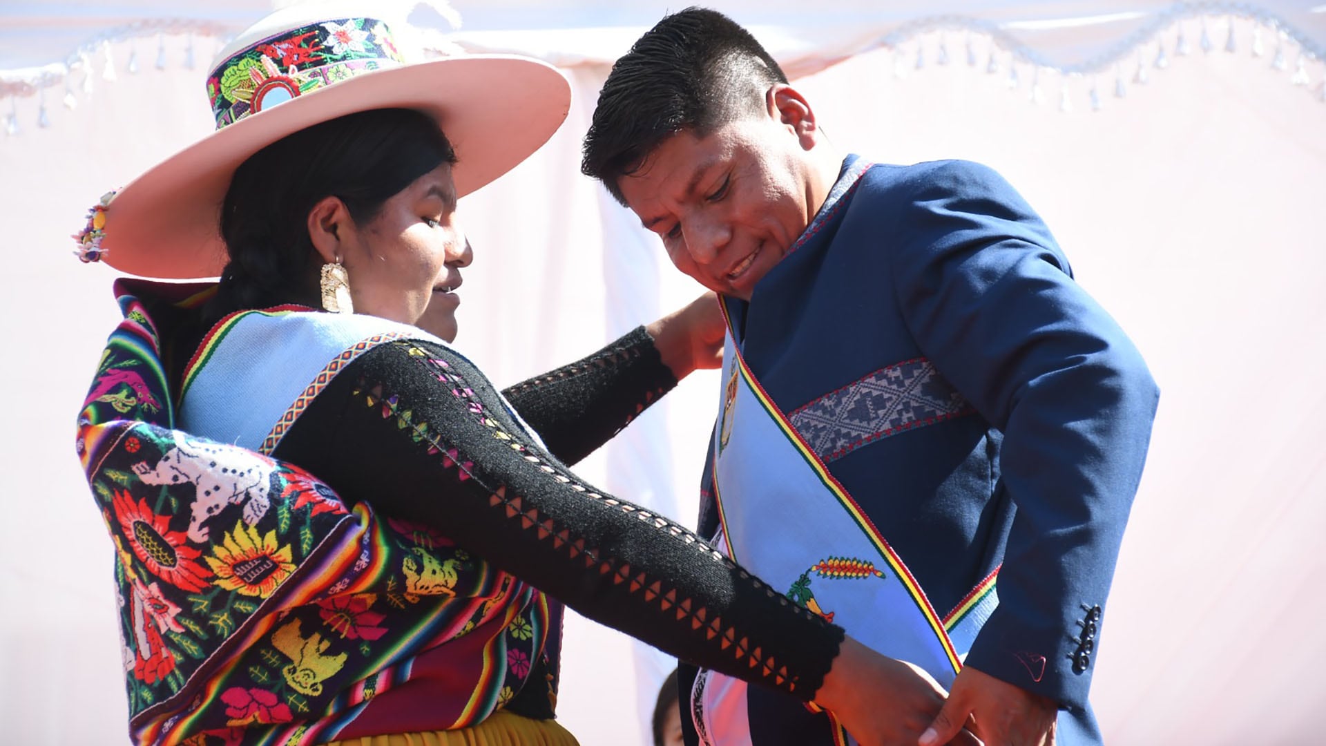Una mujer en atuendo tradicional ajusta la banda presidencial a Leonardo Loza durante su posesión como gobernador de Cochabamba este lunes.
