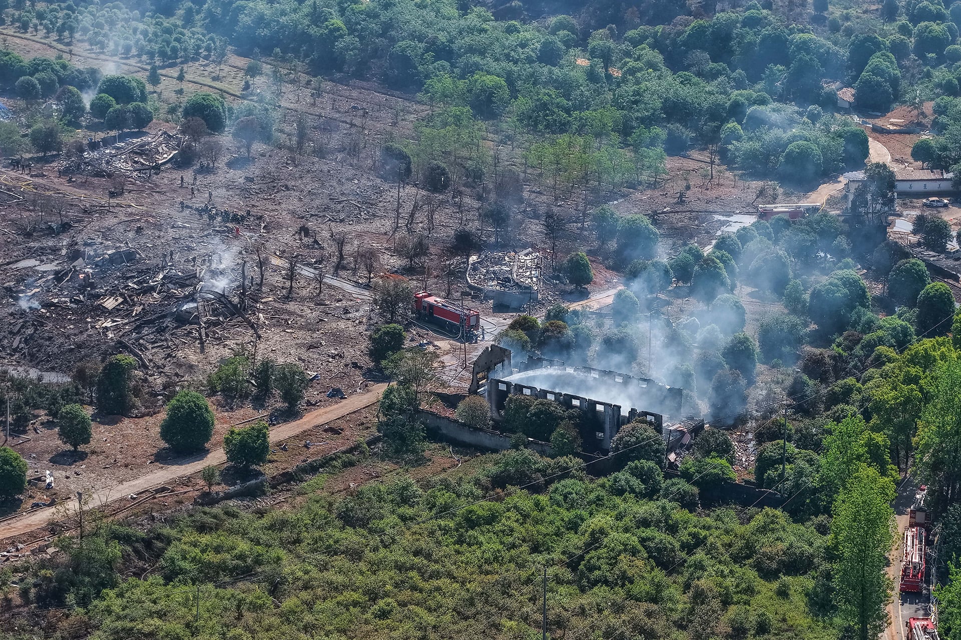 Vista aérea muestra el extenso daño causado por una explosión en una fábrica de fuegos artificiales en Liuyang, con bomberos trabajando entre escombros y humo. (AP News)