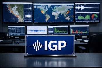 Vista frontal de una sala de monitoreo sísmico con un cartel del IGP en el centro. Al fondo, ocho monitores muestran mapas geográficos y gráficos de actividad telúrica.