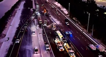 Vista aérea de la Sawgrass Expressway de noche, mostrando un accidente con camiones, vehículos policiales, grúas y escombros en la carretera