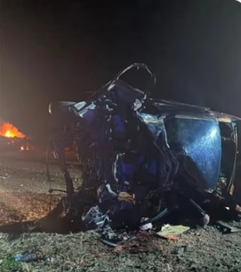 Un vehículo de gran tamaño yace volcado sobre una carretera nocturna mientras gruesas llamas y humo se elevan desde su estructura