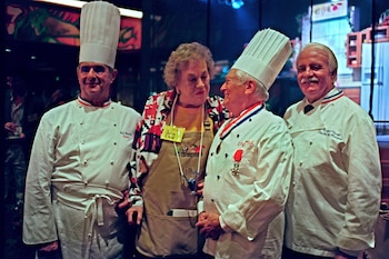 Cuatro personas: tres hombres con chaquetas y gorros de chef, y una mujer con delantal. Etiquetas identifican a Julia Child, Paul Bocuse, Roger Vergé y Lenore