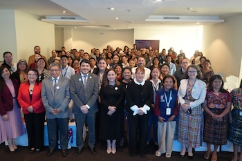 Seis mujeres sentadas en un escenario frente a una pantalla azul con la inscripción Encuentro Nacional PLANEA