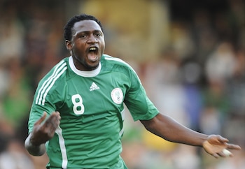 Primer plano de Michael Eneramo, un jugador de fútbol con camiseta verde número 8, gritando y con los brazos levantados en un campo