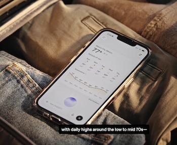 Teléfono inteligente Apple en primer plano que muestra una aplicación del tiempo, sobre tela de mezclilla y khaki