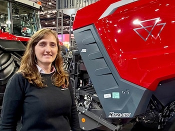 Una mujer sonríe frente a una máquina agrícola roja con la inscripción XTRA-CUT y el logo de Massey Ferguson, y un tractor rojo