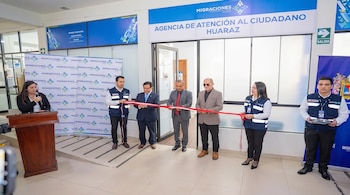 Siete personas, cuatro hombres y tres mujeres, cortan una cinta roja frente a un cartel "Agencia de Atención al Ciudadano Huaraz" y un podio con una mujer hablando
