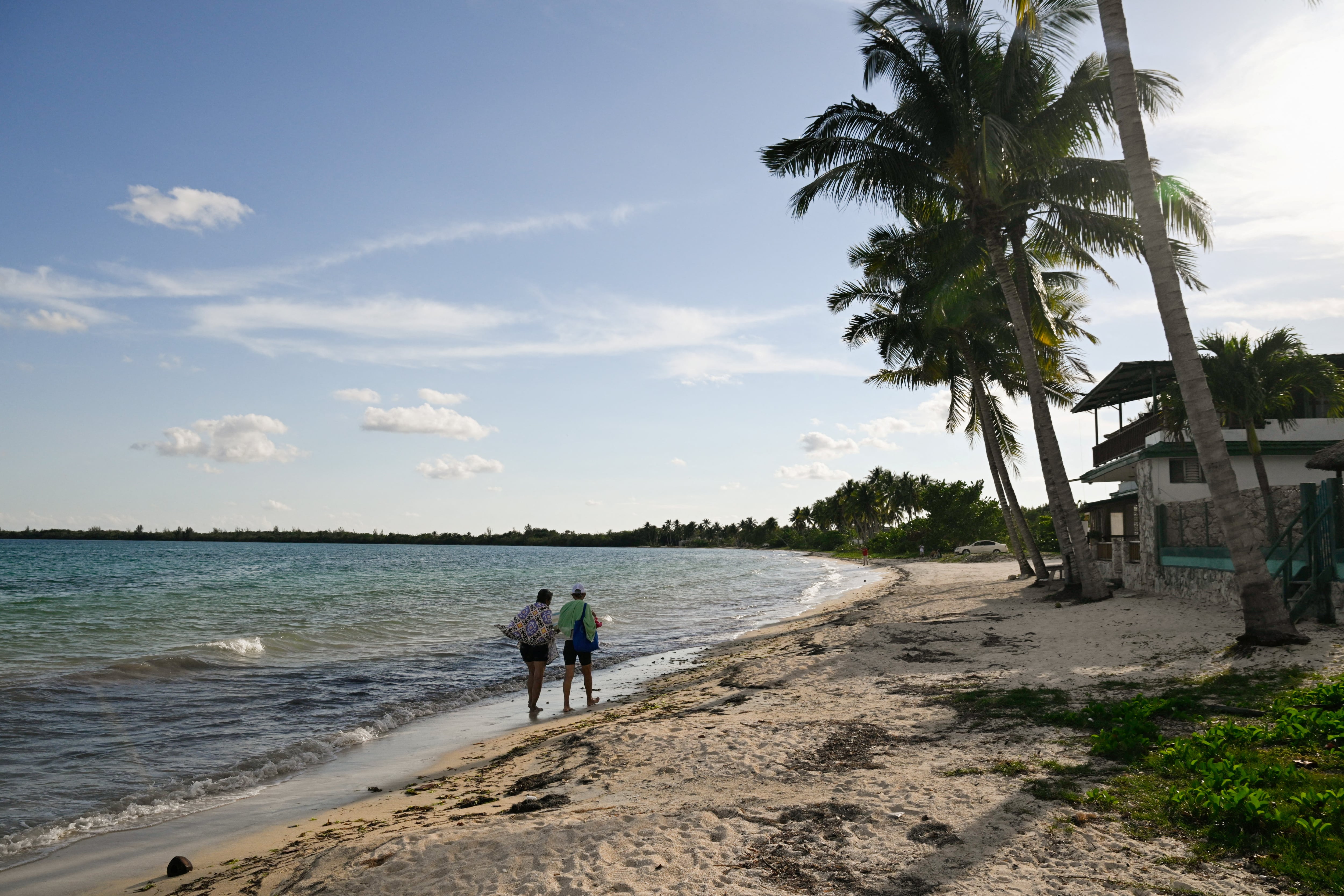 Varias personas caminan cerca de casas de alquiler mientras los principales destinos turísticos de Cuba permanecen desiertos debido a la escasez de energía y combustible impuesta por las sanciones estadounidenses. La llegada de turistas internacionales se desplomó un 56% en febrero con respecto al año anterior, en Playa Larga, Ciénaga de Zapata, Cuba, el 7 de abril de 2026. REUTERS/Norlys Pérez