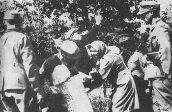 Fotografía en blanco y negro muestra al menos cinco personas: tres con uniforme militar y gorra, y dos con pañuelos en la cabeza, en un entorno de árboles y follaje