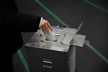 Un votante deposita cuidadosamente su