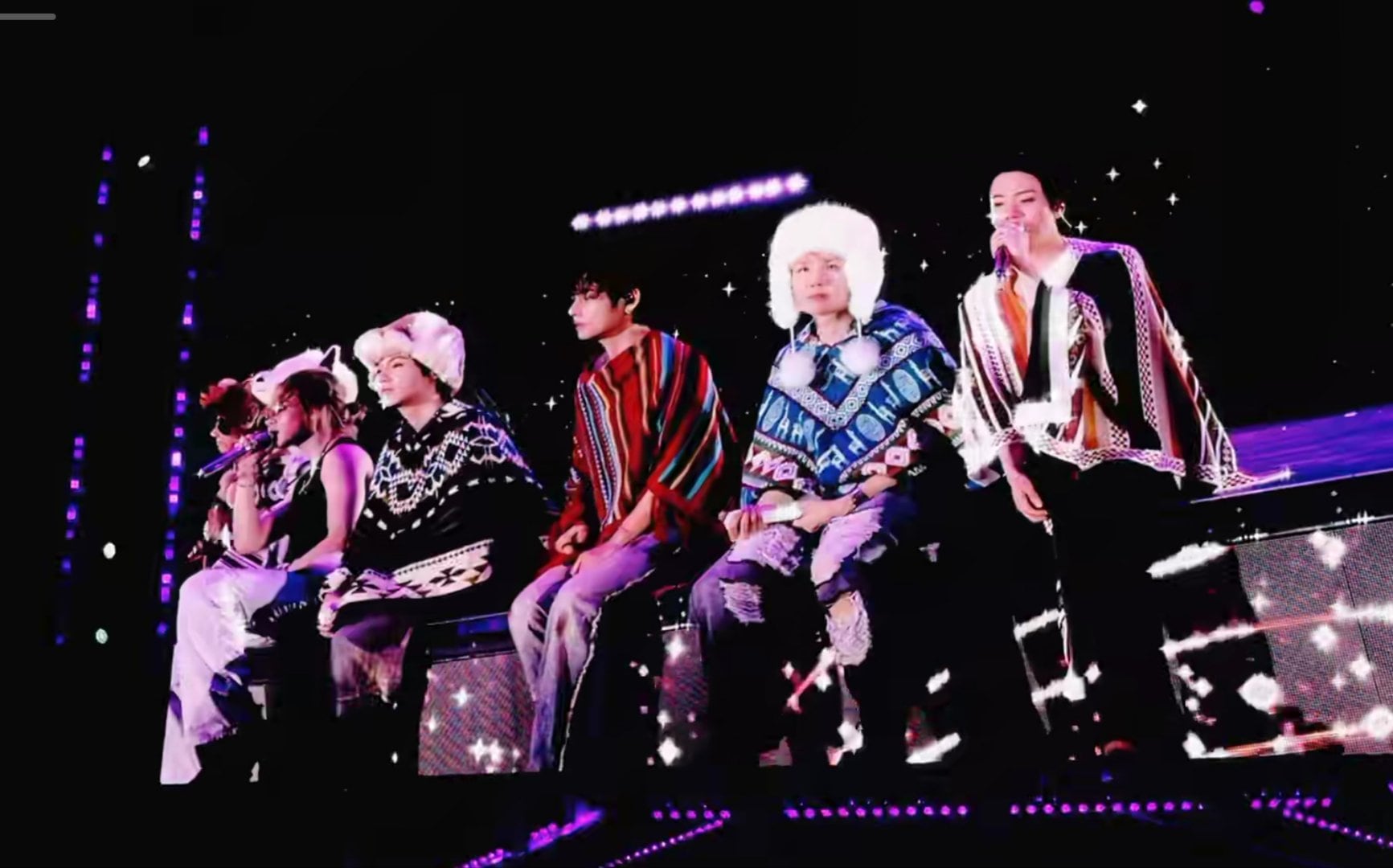 Los integrantes de la banda surcoreana BTS cantan sobre el escenario vestidos con ponchos tradicionales durante un concierto en Lima