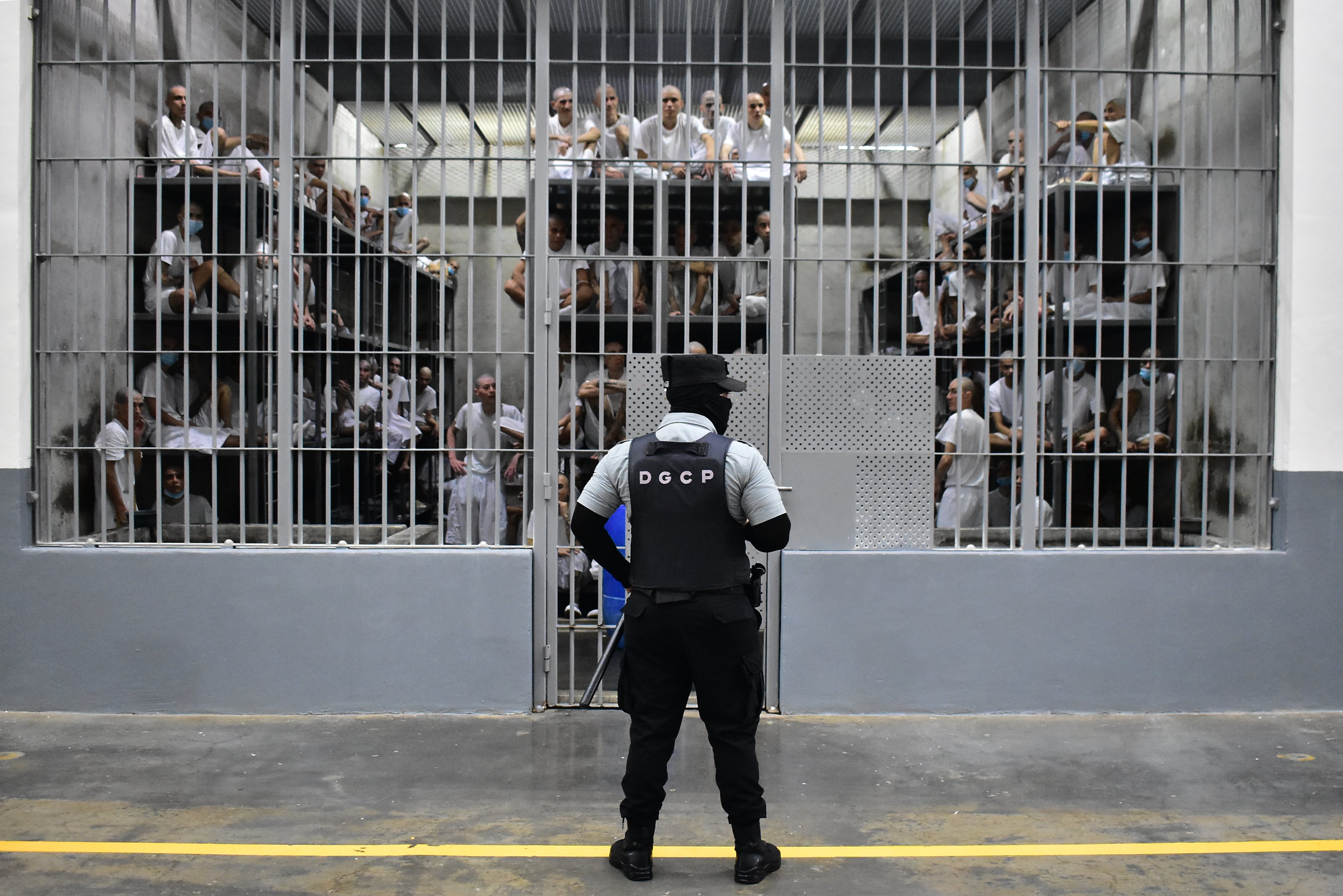 Un custodio de la Dirección General de Centros Penales monta guardia en una de las celdas de uno de los ocho pabellones que tiene esta mega cárcel. Al interior, al menos 100 pandilleros observan guardan una larga estancia en frías camas de metal. (Infobae Centroamérica/Emerson Del Cid)