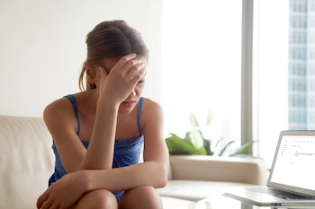 Una mujer cabizbaja se tapa la capa, visiblemente triste o afectada