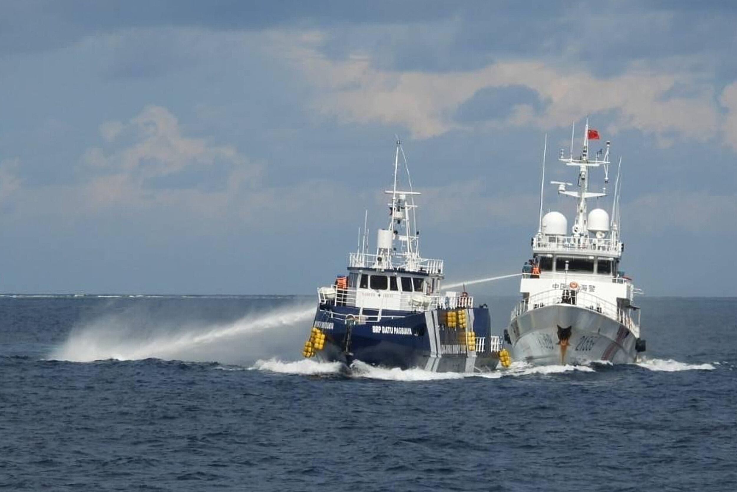 En esta imagen proporcionada por la Guardia Costera filipina, un barco de la Guardia Costera china, a la derecha, emplea su cañón de agua contra la embarcación filipina BRP Datu Pagbuaya, cerca de la isla Thitu, ocupada por Filipinas y también llamada Pag-asa, en el mar de China Meridional, el domingo 12 de octubre de 2025 (Guardia Costera filipina via AP)