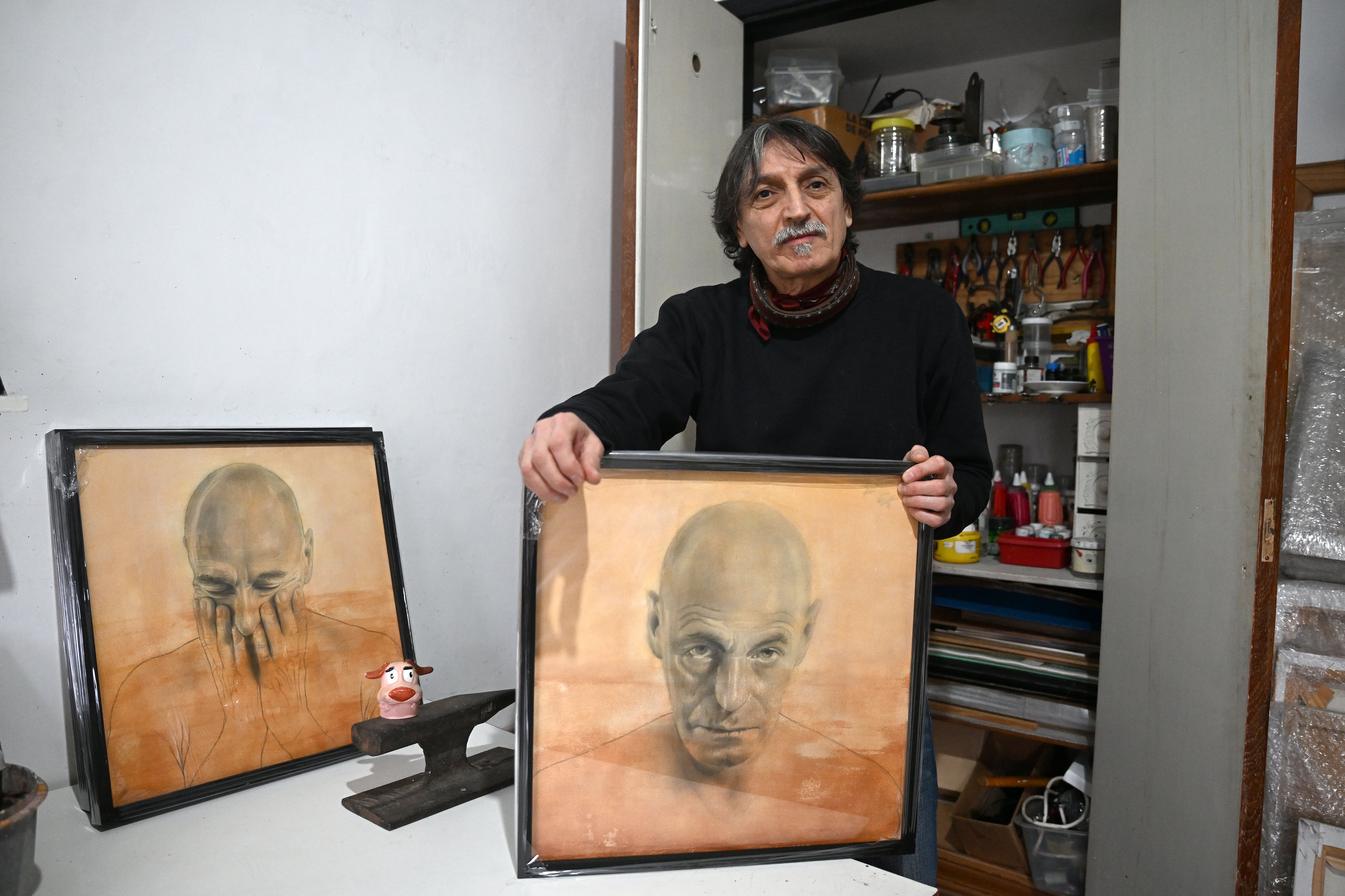 Santiago Raffo con parte de su producción artística en su casa/atelier en Saavedra. Hoy inaugura una muestra propia en Avellaneda con algunos de estos retratos. (Maximiliano Luna)