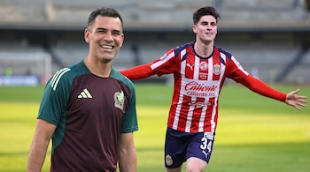 Jaime Lozano y Yael Padilla sonriendo en un campo de fútbol. Lozano viste camiseta de la Selección de México, y Padilla, con la de Chivas a rayas rojas y blancas.