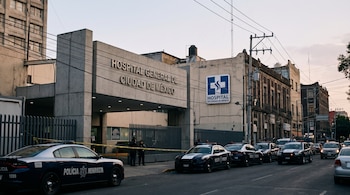 Edificio de Hospital General de Ciudad de México al atardecer, con letrero institucional, varias patrullas de policía y cinta amarilla de seguridad.