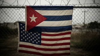 Banderas de Cuba y Estados Unidos colgadas en una reja metálica con alambre de púas