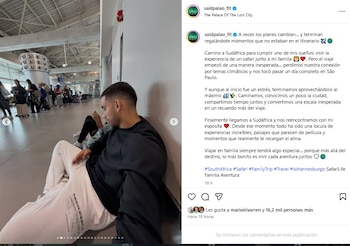 Said Palao, un hombre de cabello corto y barba, sentado en el suelo de un aeropuerto con camisa negra y pantalón blanco, mirando hacia el frente. Al fondo, otras personas transitan