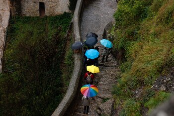 Tourists use umbrellas to cover