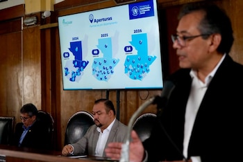 Un hombre habla en un podio frente a una pantalla que muestra mapas de Guatemala con cifras de aperturas de farmacias de 2024 a 2026