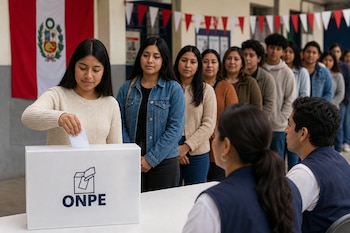 Una mujer deposita una cédula en una urna con el logo de la ONPE frente a una fila de personas y la bandera de Perú.