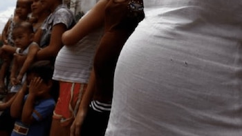 Primer plano de varias personas de pie, incluyendo adultos y niños. Un niño en primer plano cubre su rostro con las manos. Los demás aparecen desenfocados