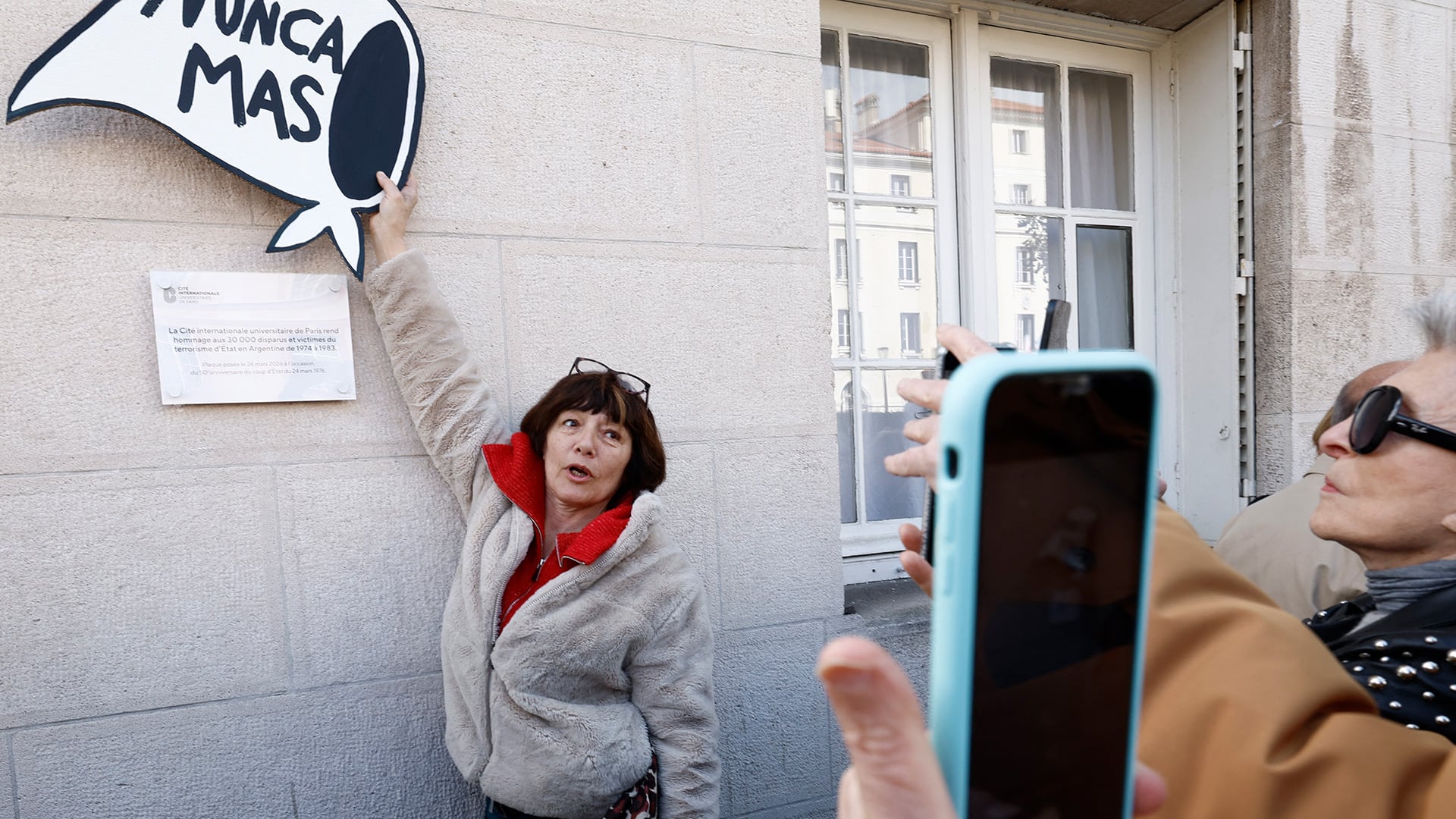 Una mujer se fotografía con la flamante placa que recuerda a los desaparecidos, en París.