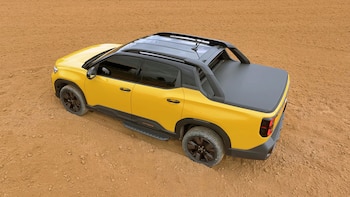 Camioneta pickup de color amarillo y negro en un terreno de tierra visto desde una perspectiva elevada