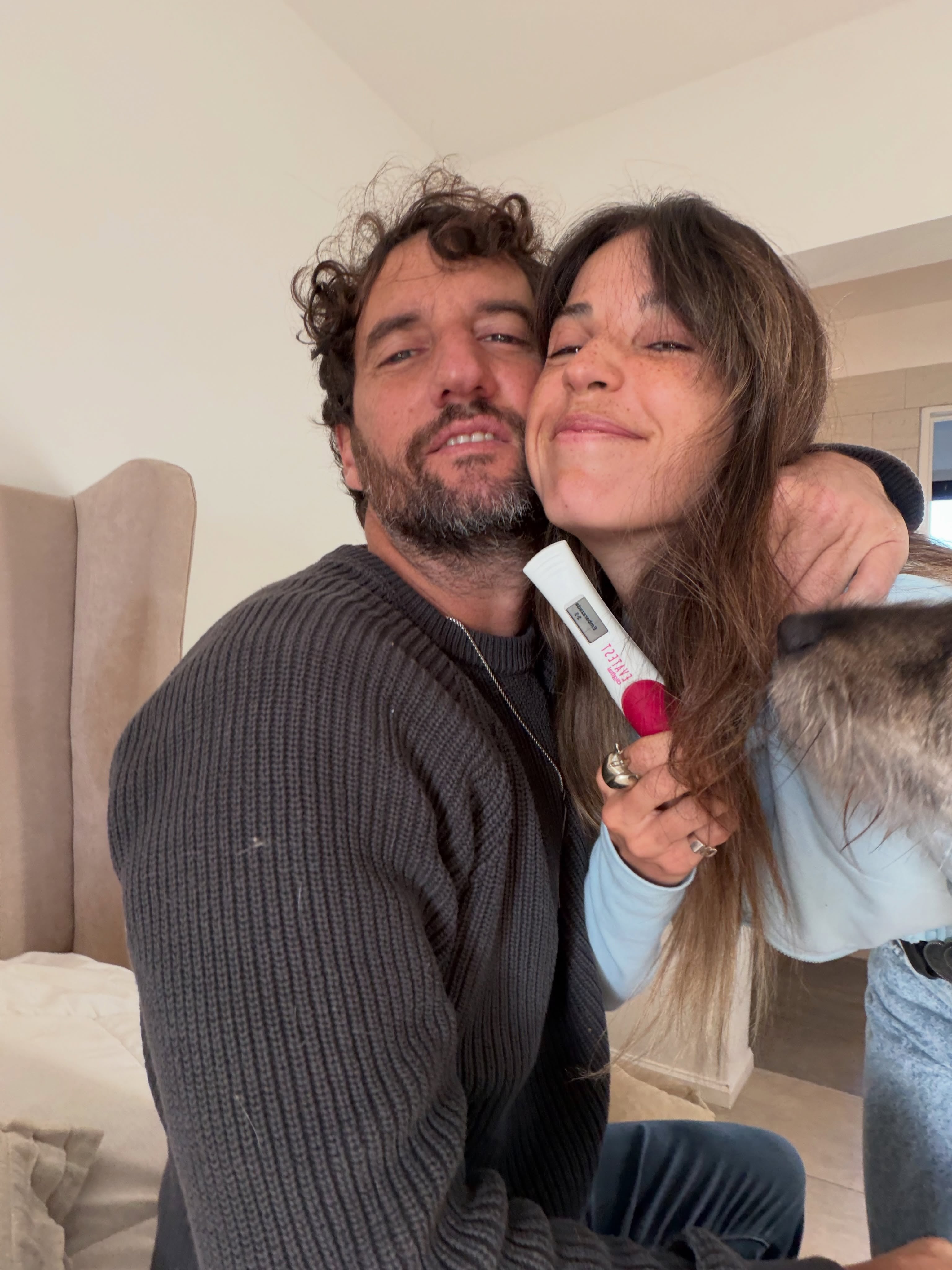 Cande Molfese y su pareja abrazados muestran un test de embarazo con resultado positivo que indica su futura paternidad.