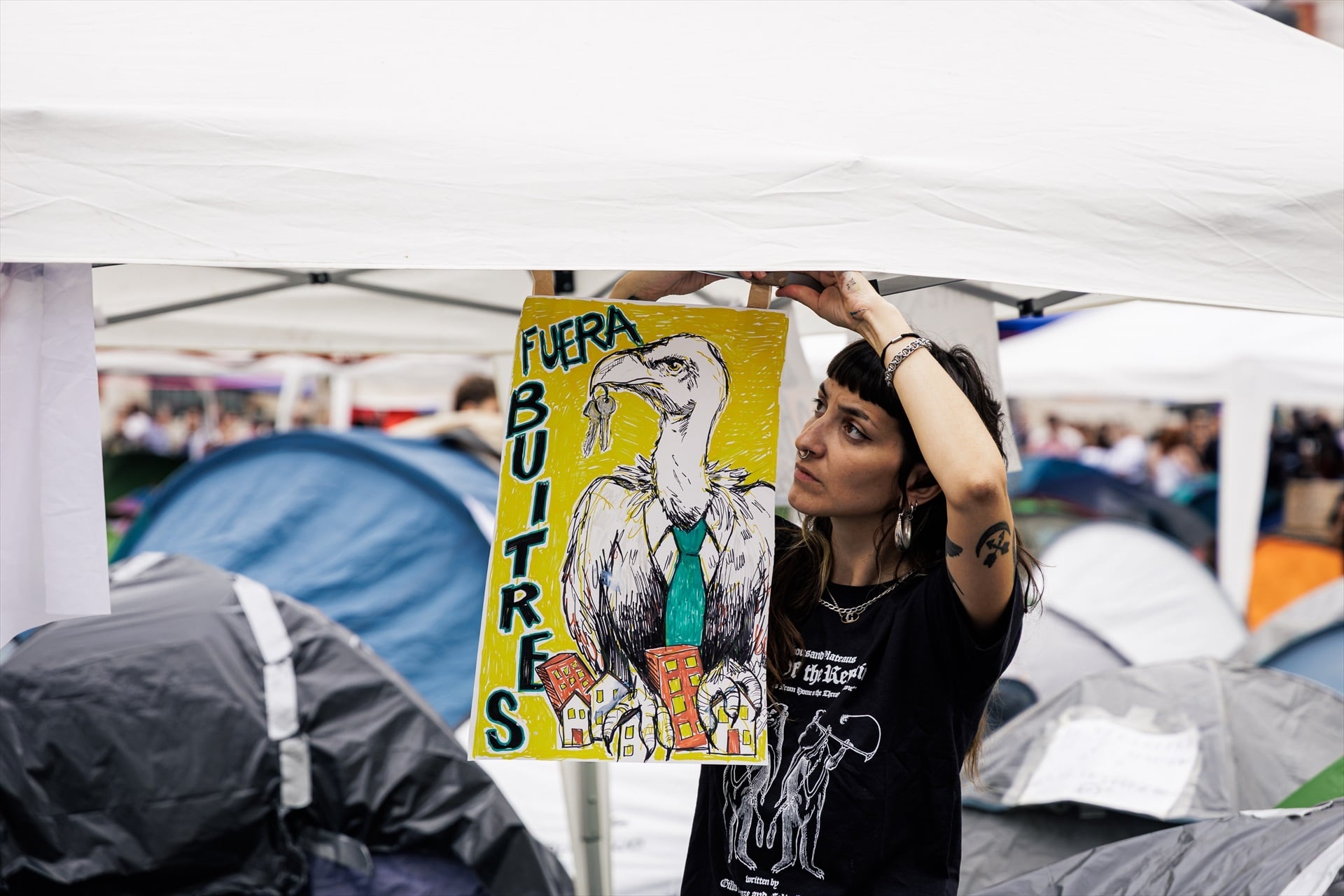 Una chica cuelga un cartel en la acampada, en la Puerta del Sol (Madrid). (Carlos Luján / Europa Press)