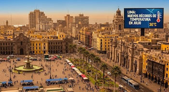 Plaza Mayor de Lima, edificios coloniales, fuente, personas, palmeras y cartel digital con 30°C y texto sobre récords de temperatura.