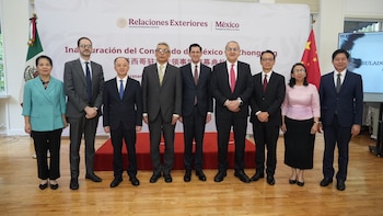 Nueve personas en traje posan alineadas frente a un cartel de inauguración junto a las banderas de México y China