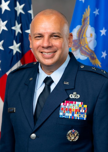 Retrato de Frank Verdugo, Mayor General de la Fuerza Aérea de EE. UU., sonriendo y vistiendo uniforme azul marino con insignias y condecoraciones