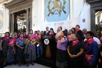 Una mujer habla ante un atril del Congreso de la República rodeada de personas con pañuelos de color rosa al cuello