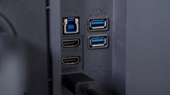 Panel plástico con dos entradas HDMI, tres puertos USB y un cable negro conectado en la base.