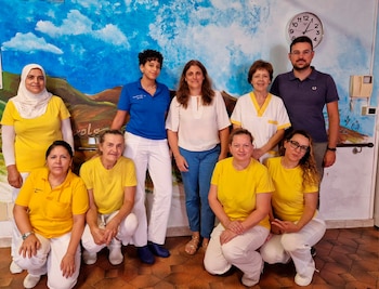 El equipo de trabajo de uno de los turnos: de azul, la enfermera; las de amarillo son las operadoras socio sanitarias: una olombiana, una peruana, una polaca, una marroqui, una italiana y una albanesa. En el centro, de camisa blanca, Sonia Messina