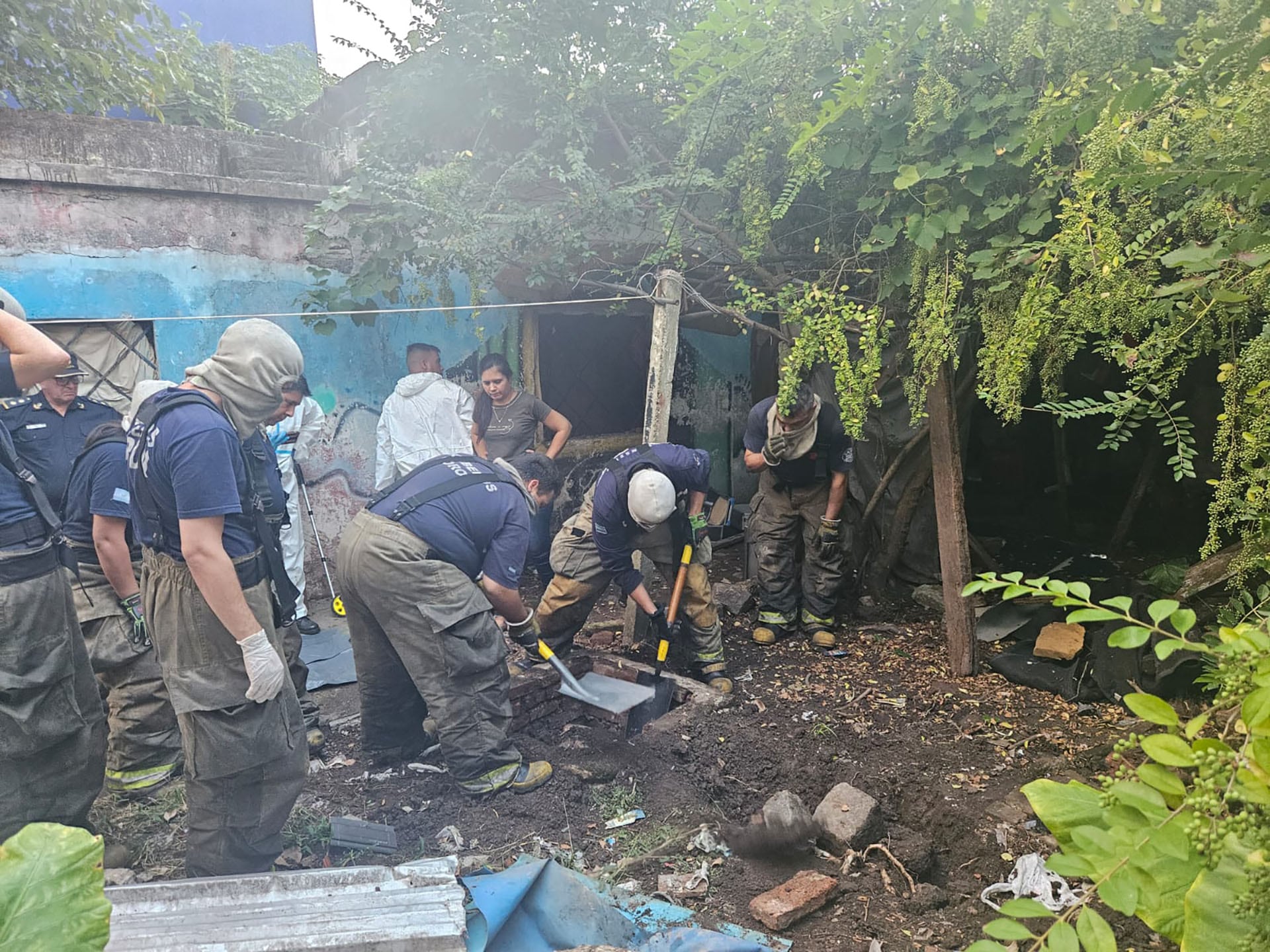 Investigadores forenses y personal de seguridad excavan en un terreno baldío durante la investigación de la escena del crimen del rapero Mike Dee