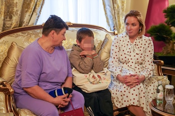 Un niño ucraniano de 7 años de edad, que fue el primer niño liberado bajo un nuevo mecanismo que Qatar ha establecido con el objetivo de repatriar a los niños de Rusia a Ucrania, está sentado junto a su abuela y la Comisionada de Rusia para los Derechos del Niño, Maria Lvova-Belova después de ser liberado a los diplomáticos qataríes en esta imagen tomada en la embajada de Qatar en Moscú, Rusia, el 13 de octubre de 2023 (REUTERS)