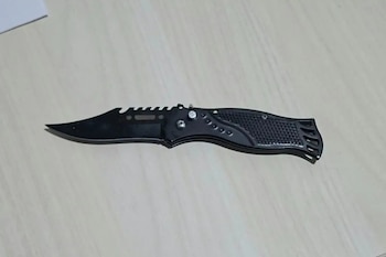 Una navaja plegable de color negro desplegada sobre una mesa de tono claro