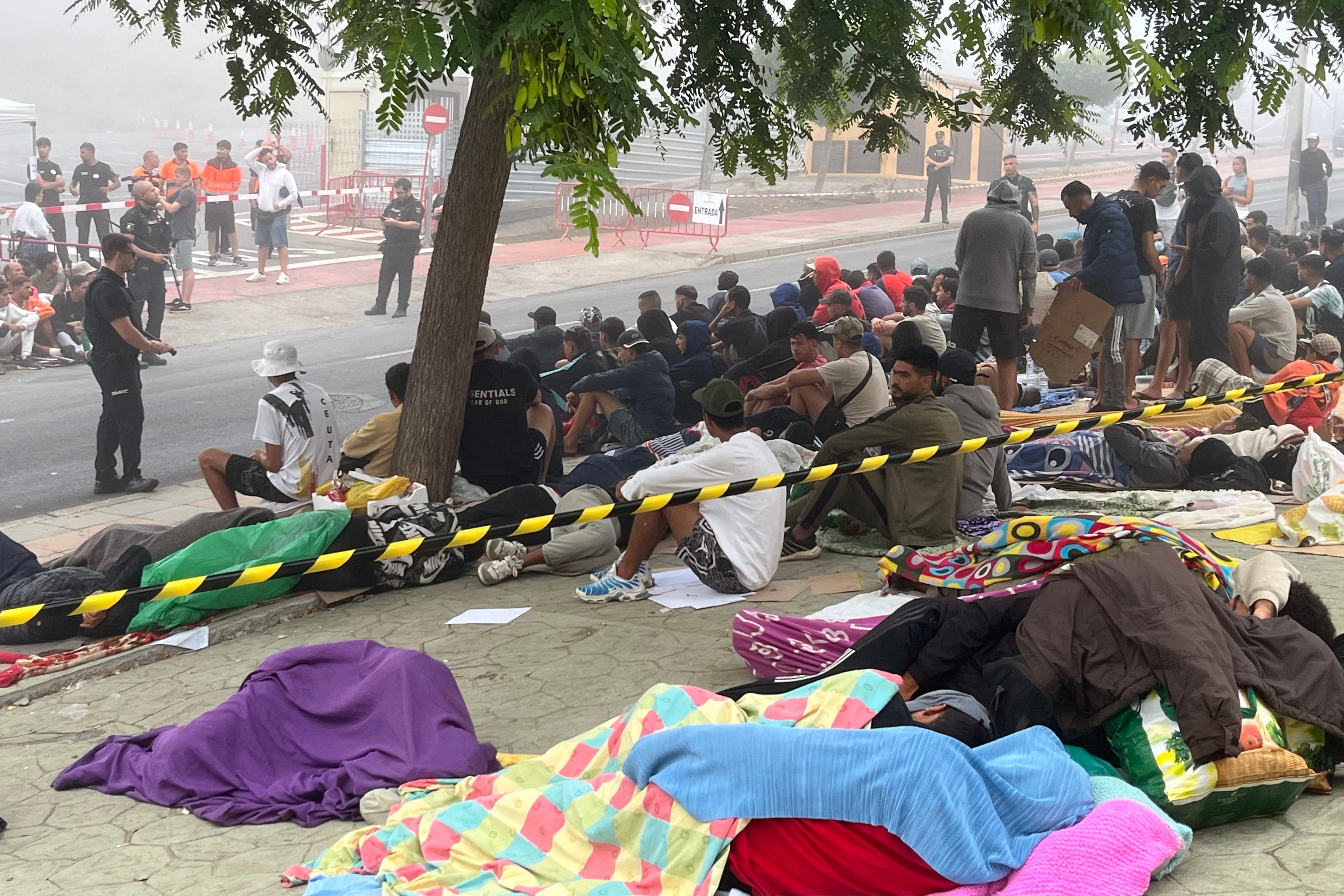 Decenas de personas se concentran cerca del embolsamiento de Loma Colmenar con la esperanza de conseguir una plaza en un nuevo centro de acogida. (EFE/Reduan)