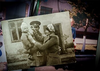 Fotografía en blanco y negro de un hombre con gorra militar, una mujer y un bebé en brazos
