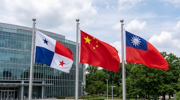 Tres banderas de Panamá, China y Taiwán ondean en astas de metal ante un edificio de vidrio y árboles bajo un cielo nublado.