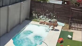 Hombre intentando limpiar con un saca bichos la pileta llena de espuma mientras su cuñada graba la escena
